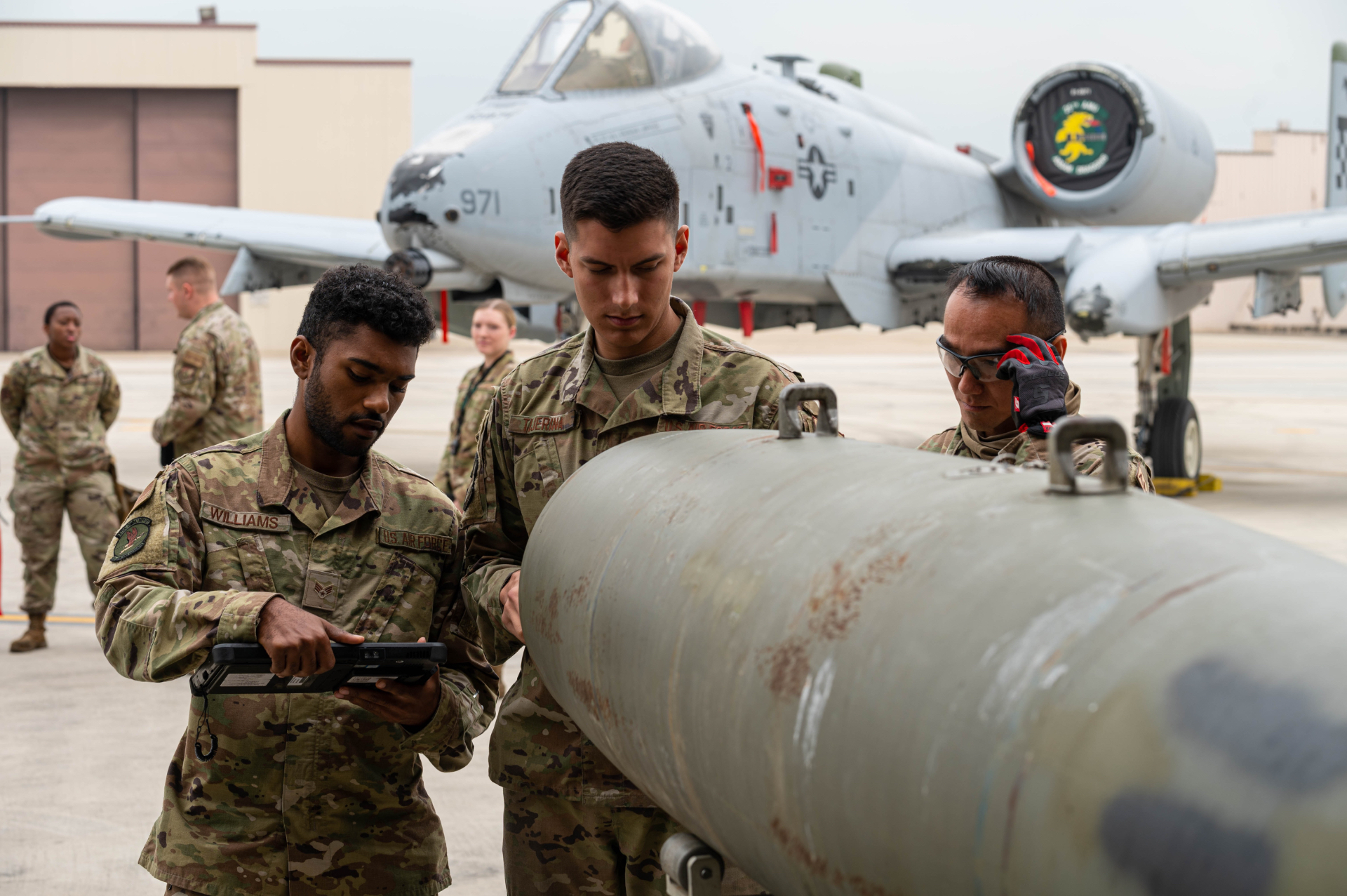 Air Force personnel working on the flightline with an aircraft in the background